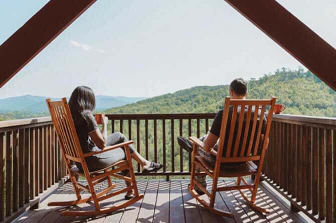 Two people sit in rocking chairs and admire the mountain view at one of the best campgrounds for couples