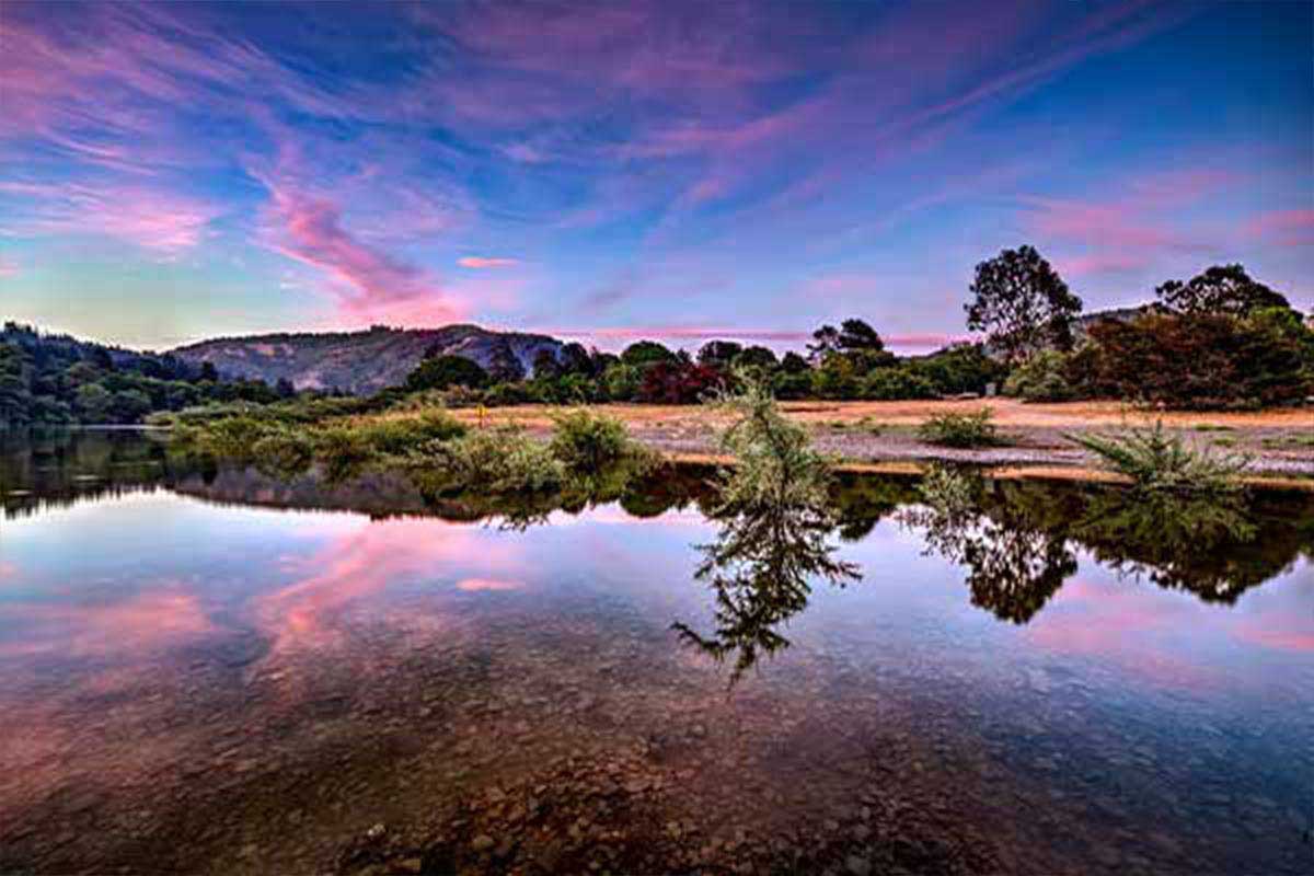 A blue and purple sunset is reflected over the water at Casini Ranch Family Campground