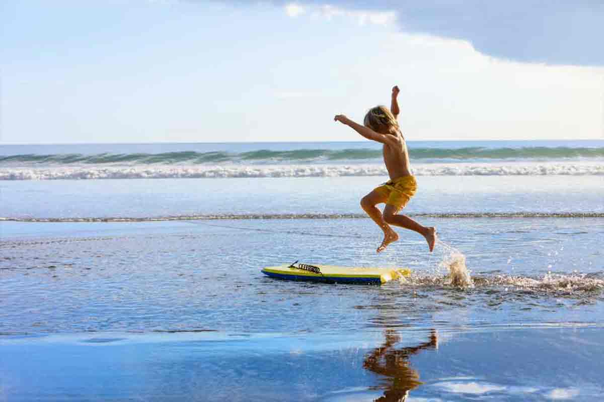 Boy on skim board in pacific ocean at Paradise by the Sea Beach RV Resort