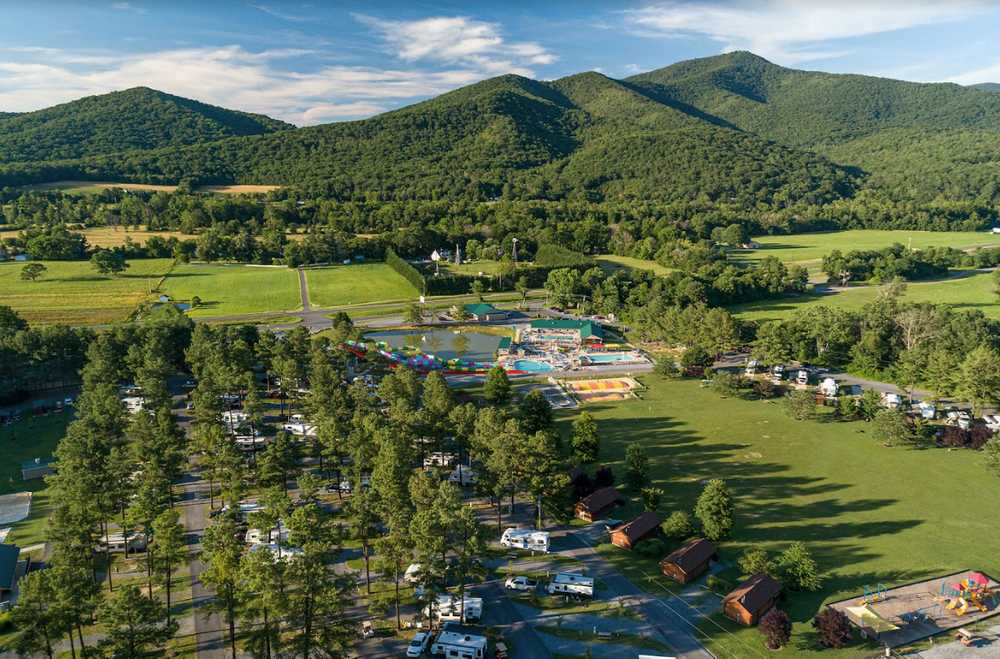 Campground drone shot with mountains, pond, jumping pillow, water park and RV sites at Jellystone Park Luray.