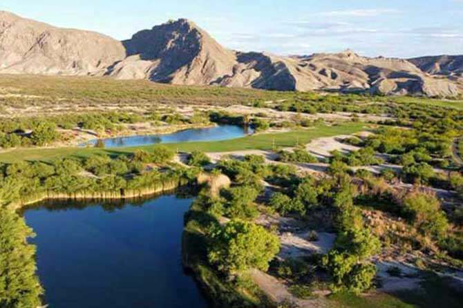 A blue body of water is surrounded by greenery and mountain views outside of Maverick Ranch RV Park