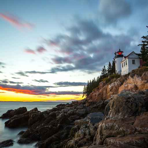 A lighthouse sits on a craggy cliff overlooking the ocean at Acadia National Park, a top 2023 camping destination