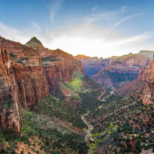 A thin river winds at the bottom of a deep ravine at Zion National Park, a top 2023 camping destination